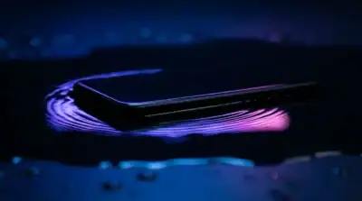 Smartphone moderne posé sur une surface réfléchissante avec des ondes sonores lumineuses pour une sonnerie personnalisée
